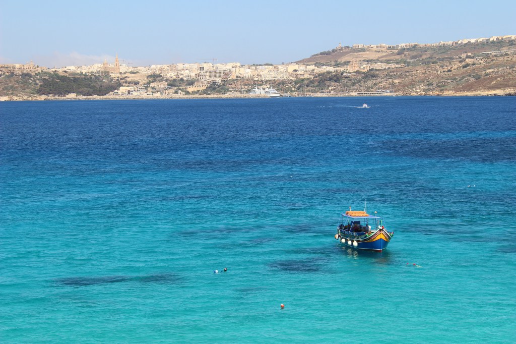 Picture of a colorful boat in the sea with an island landscape in the background