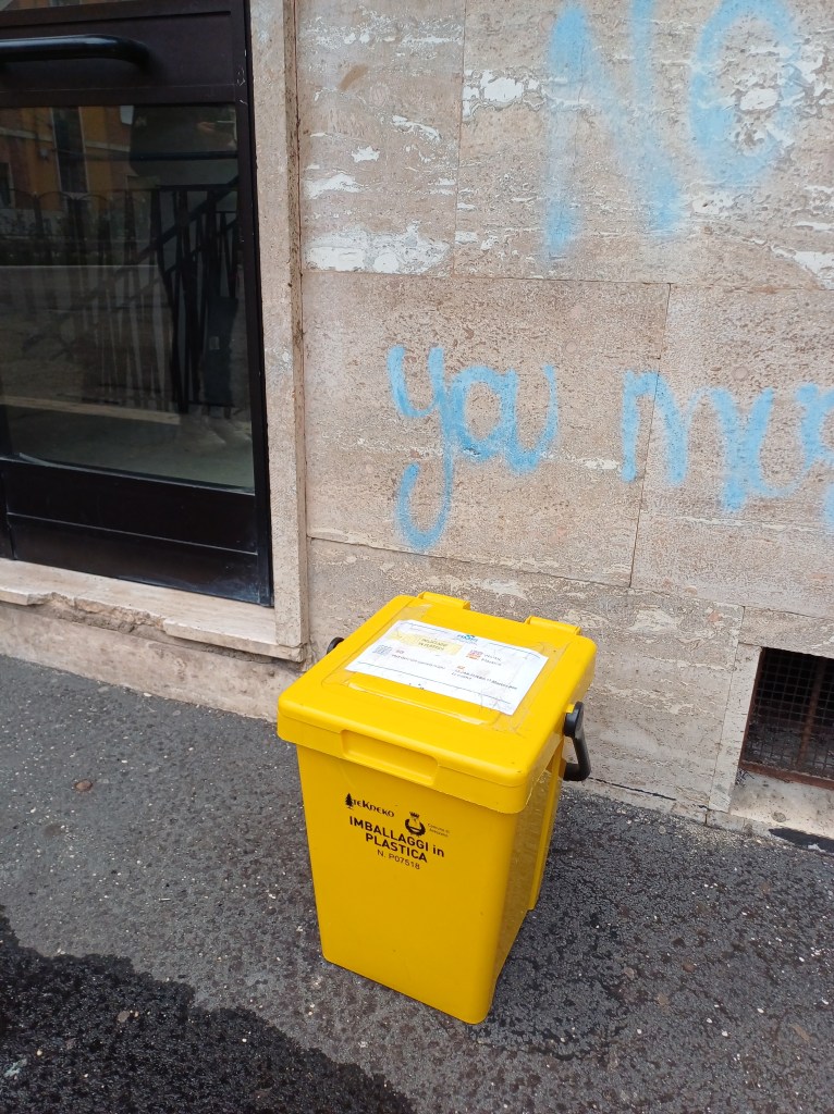 Keltainen jäteastia talon edessä.