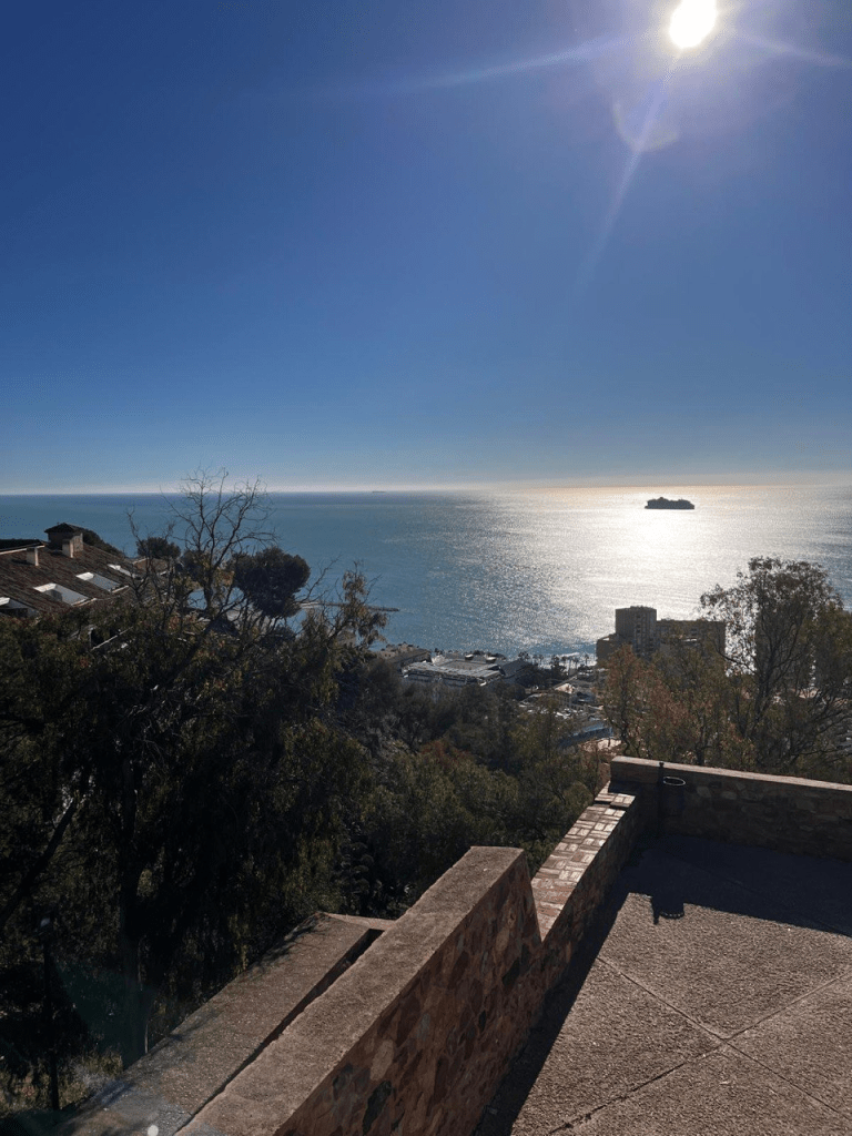 Kalliolta otettu kuva Caditzista missä näkyy luontoa, rakennuksia, merinäkymä ja yksinäinen saari.