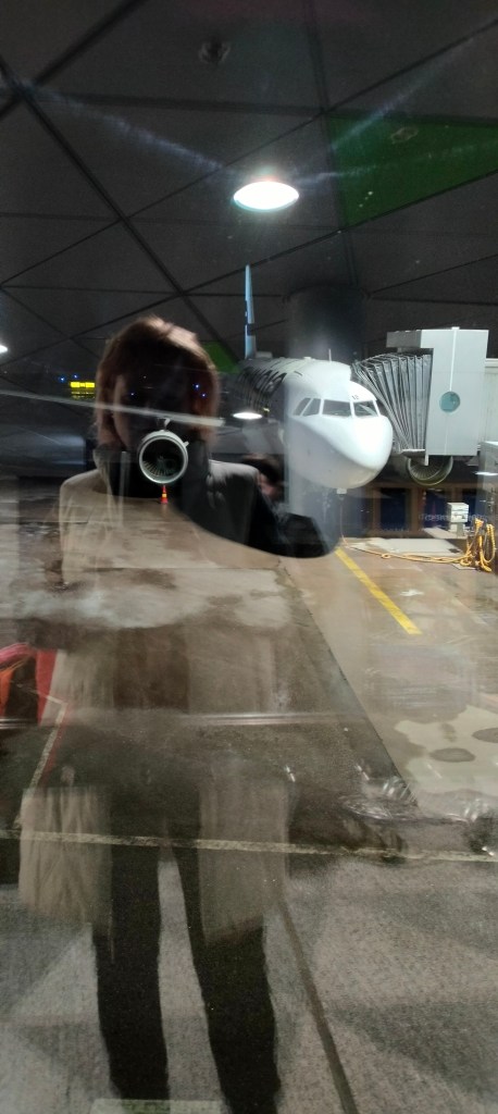 Lentokentällä ikkunan läpi otettu kuva lentokoneesta