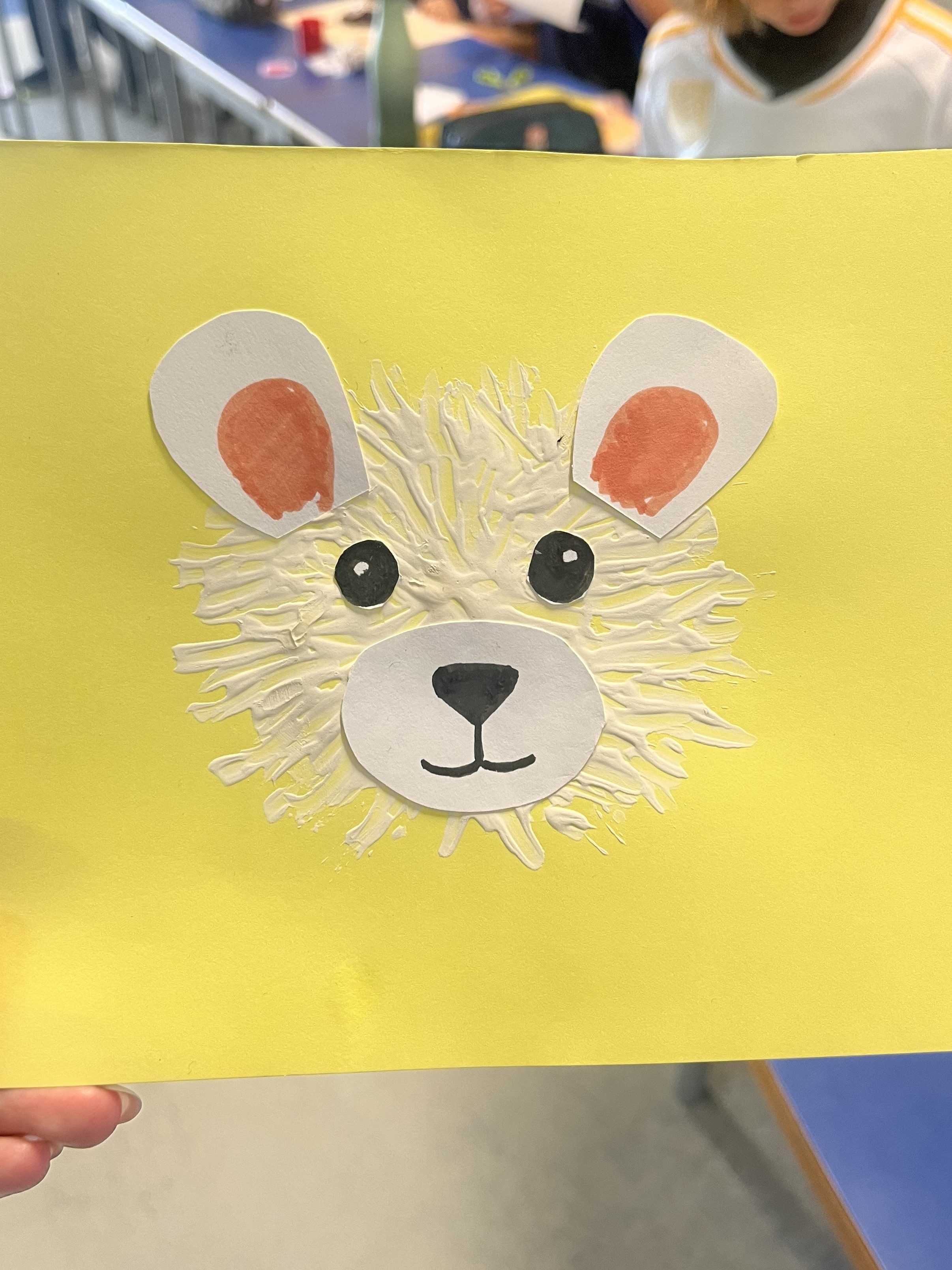 A painting of a polar bear cub on a yellow paper made by a teacher as an example for the students for art class.