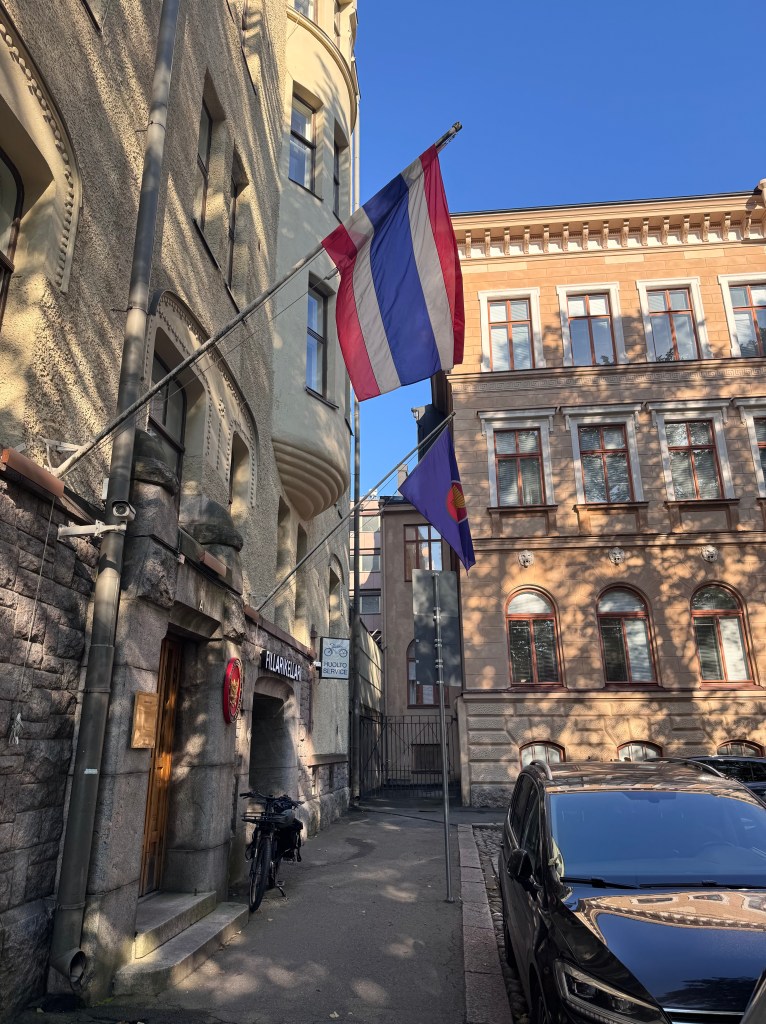 Kuva Helsingistä Thaimaan suurlähetystöstä. Kuvassa on vanha keltainen rakennus josnkan oven yläpuolella liehuu Thaimaan lippu. 