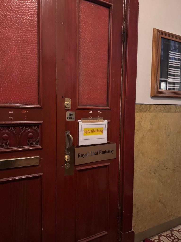 Kuvassa on punainen ovi jossa on kyltti jossa lukee"Royal Thai Embassy"