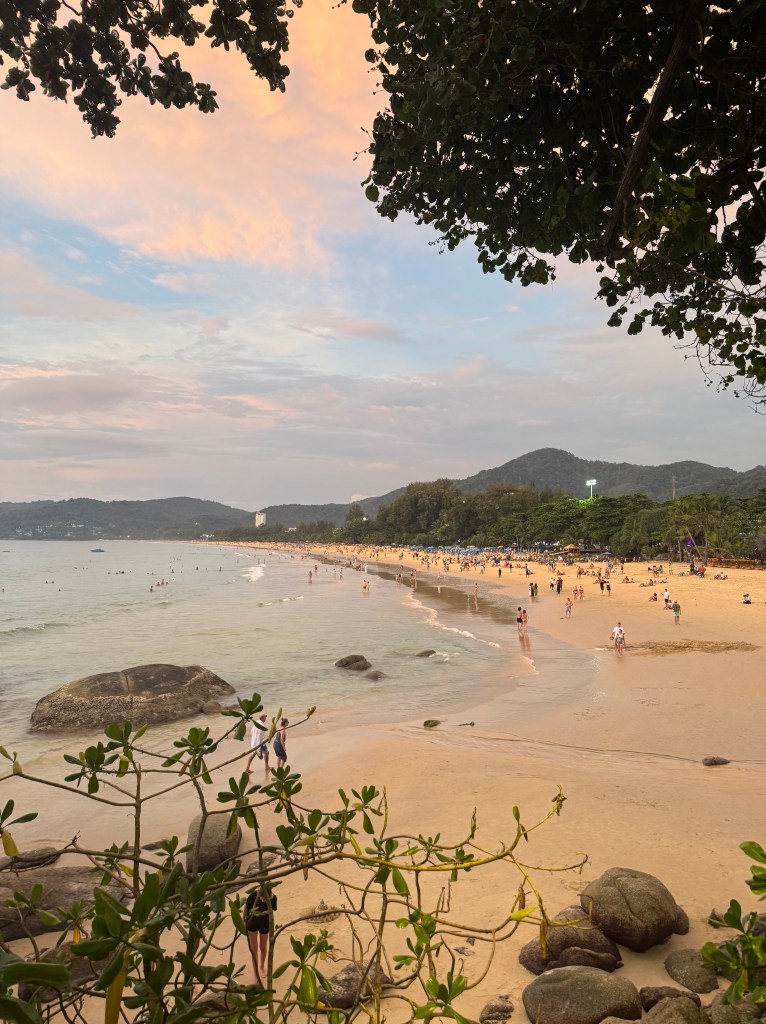 Kuvassa on kaunis sini-oranssi taivas, sinistä vettä ja hieman kasvillisuutta. 